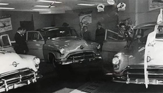 Vintage photo of classic cars displayed in a showroom, showcasing their design and style from a bygone era.